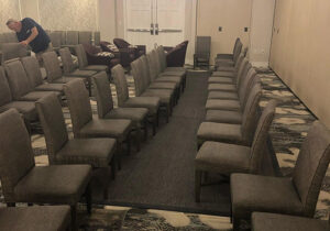 Technician cleaning upholstered banquet chairs in a function room