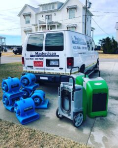 Masterclean van with air movers and a dehumidifier outside a coastal home