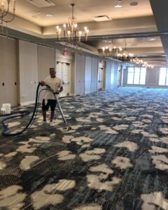 Technician cleaning patterned carpet in a ballroom