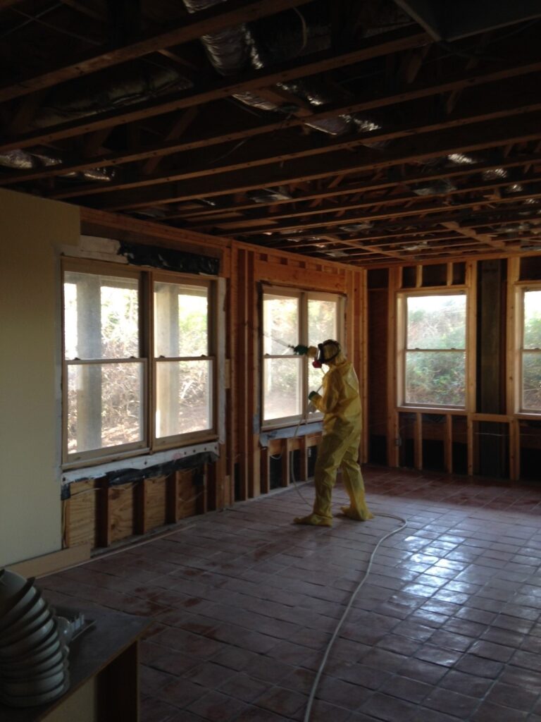 Mold remediation technician in protective gear in a gutted room