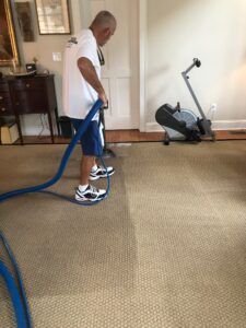 Technician cleaning residential carpet with a wand